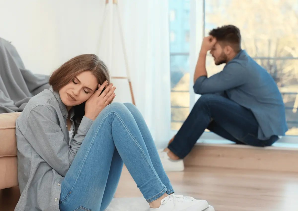 Couple sitting apart in silence, each looking down